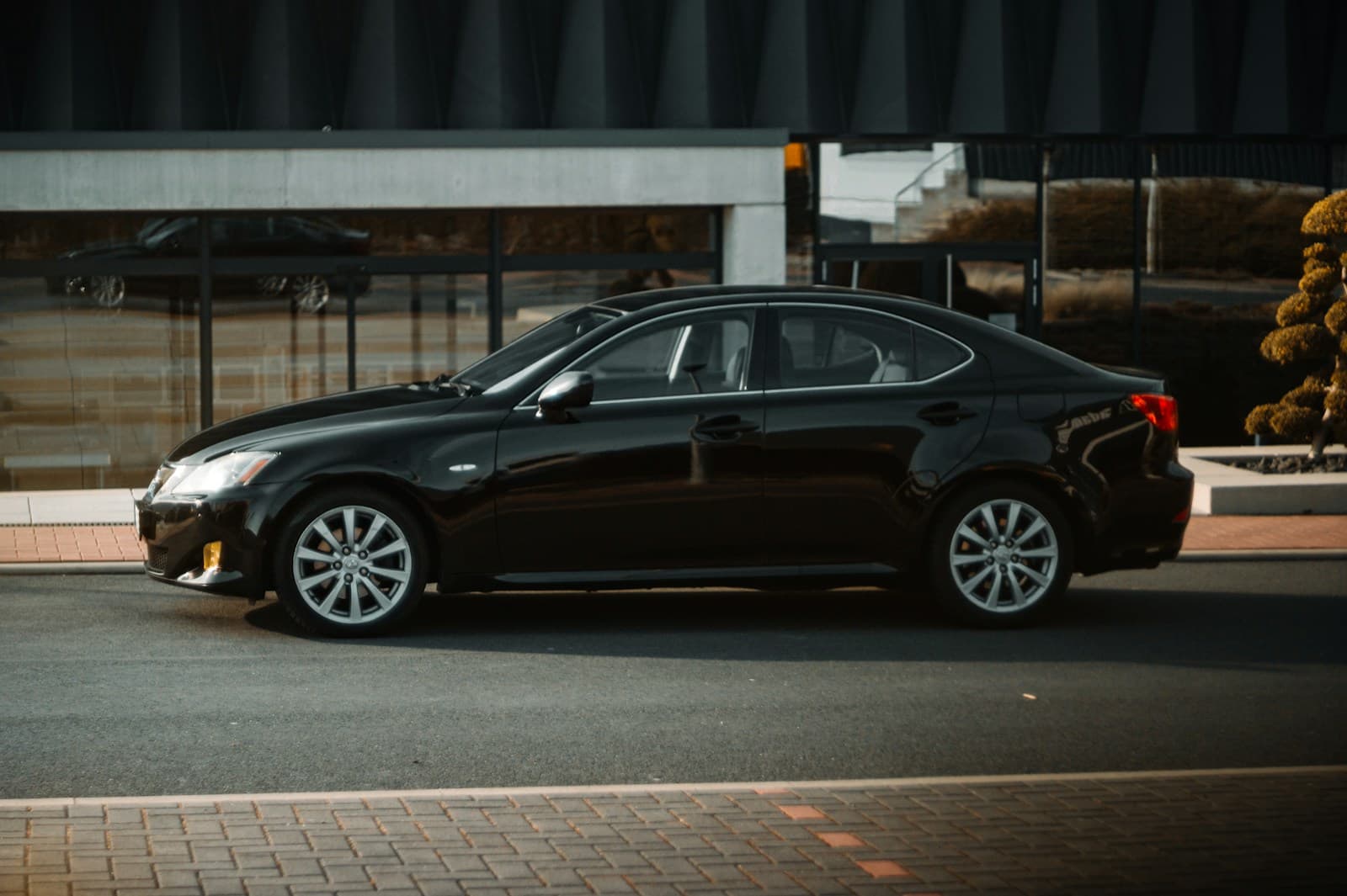 A black executive sedan parked outside a modern building